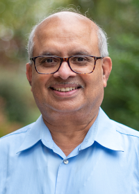 Sarma Pisupati outside smiling in front of greenery. 